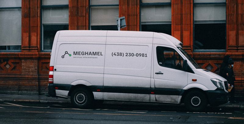 Fourgonnette blanche de Meghamel Services Informatiques avec le logo et le numéro (438) 230-0981 sur le côté